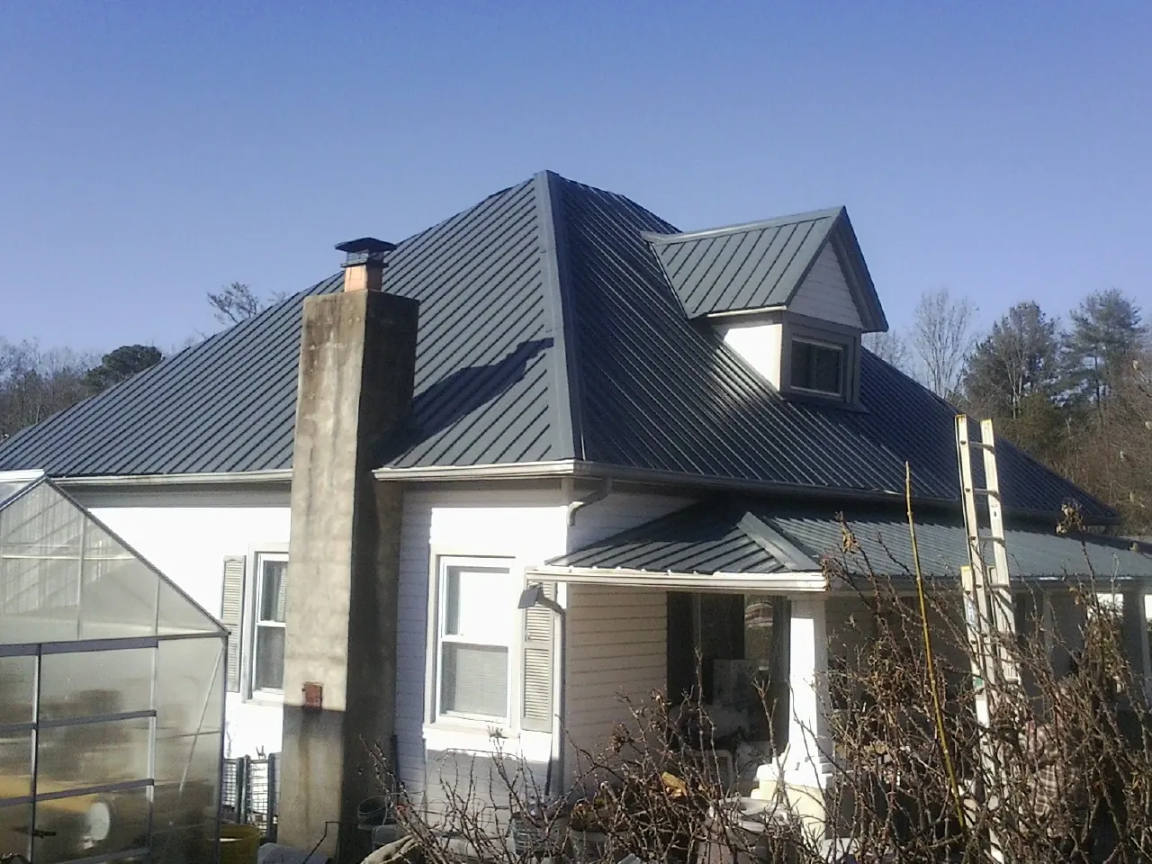 Dark blue standing seam metal roof on a white farmhouse with dormer — Slate & Tile Roof Repair by Roofing Brothers in Culloden