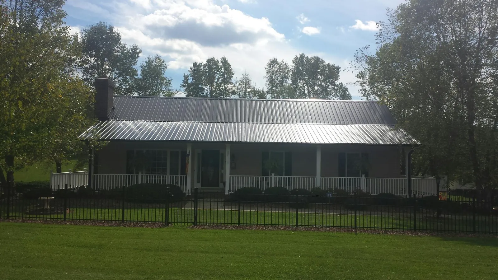 Gray metal roof on a brick ranch with a full width front porch — Gutter Guard Installation work by our crew in Culloden