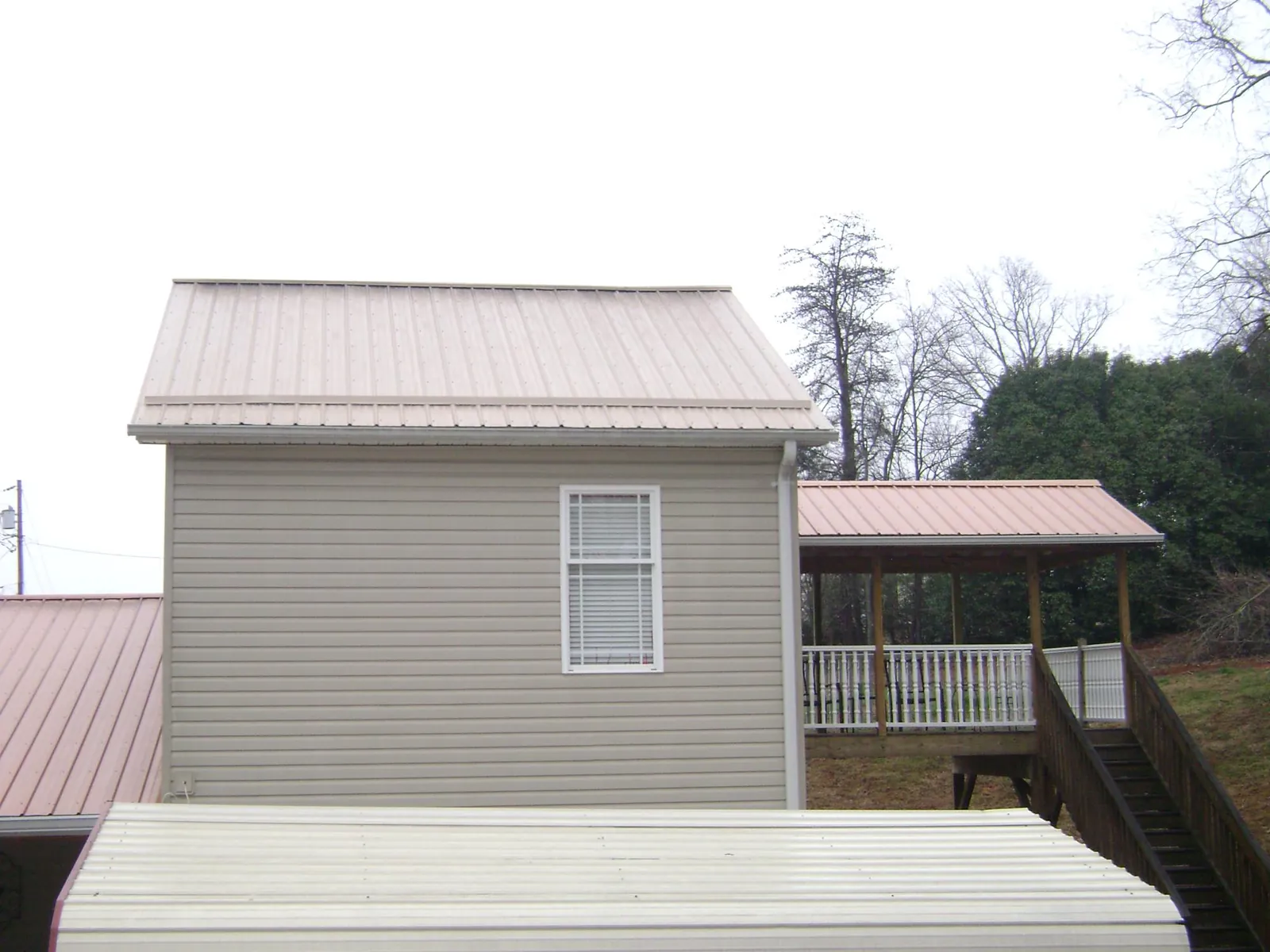 Tan metal roofs on a two story addition and attached porch, from a Roof Replacement job in Culloden