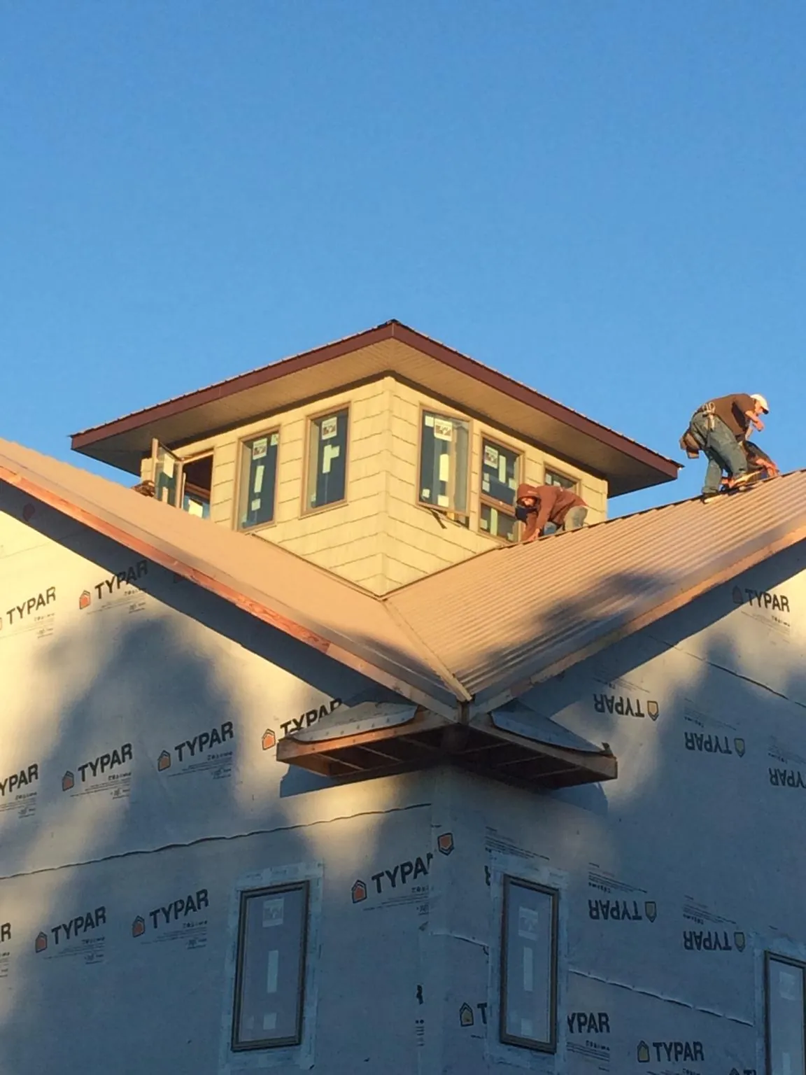Roofers working around a rooftop cupola on a new metal roof at sunset — Roof Waterproofing in Culloden by Roofing Brothers